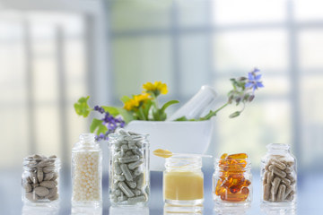 Naturopathic medicine capsules, gel tabs, and paste sit contained in glass jars on a glass table top in Lehigh Valley.
