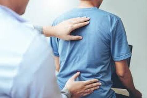 Male doctor assesses patient with back pain at a clinic in Lehigh Valley.